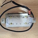 Elektrický snímač kytary s kovovým krytem a černým plastovým základem. Na spodní straně je vyražen nápis Seymour Duncan a text made in USA. Na bílých…