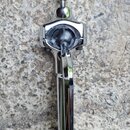 Detailní pohled na chromovaný kovový mechanismus svorky nebo držáku. Povrch je vysoce lesklý, v horní části je vidět stahovací šroub. Na předmětu nej…