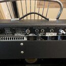 Zadní panel kytarového komba v černém texturovaném provedení. Na panelu jsou nápisy POWER, PARALLEL SPEAKER OUTPUTS a FOOTSWITCH, dále označení CE a…