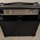 Zadní strana černého kytarového komba s rukojetí a plastovými rohy. Na bílém štítku jsou nápisy LINE 6, SPIDER IV 15 AMPLIFIER – 15 WATTS 1X8 a U.S.…
