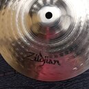 Kovový činel stříbrné barvy s výrazným kovánívým povrchem a koncentrickými rýhami v centru. Na povrchu je černý nápis Zildjian a v horní pravé části…