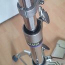 Detail chromovaného kovového stojanu s teleskopickým mechanismem a utahovacími šrouby. Na spodní části trubice je viditelný fialový nápis YAMAHA. Pov…
