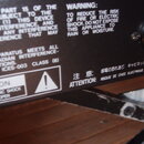 Detail zadní strany černého elektronického zařízení s bílými nápisy. Je zde viditelný 11pinový konektor s nadpisem LESLIE 11PIN. Na povrchu jsou varo…