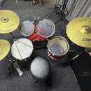 Sada červených bubnů s černým sedátkem a mosaznými činely. Na činelech je vidět nápis Zildjian a označení PLANET Z, na blanách bubnů je nápis EVANS.…