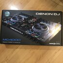 Kartonová krabice s obrázkem černého DJ kontroléru. Na krabici jsou nápisy DENON DJ, MC4000 a PREMIUM 2-CHANNEL DJ CONTROLLER. V pravém dolním rohu j…