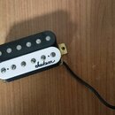 Černý humbucker s bílým plastovým krytem. Na krytu je černý nápis jackson. Snímač má připojení v podobě černého kabelu a vykazuje mírné znečištění po…