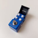 Modrý efekt pedál s kovovým šasi a čtyřmi bílými oválnými knoflíky. Na přední straně je nápis Old School a stříbrný spínací pedal. Vnitřní strana ote…