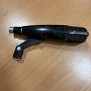 Černý mikrofon s mřížkou a připevněným držákem, položený na dřevěném povrchu. Tělo mikrofonu vykazuje viditelné známky opotřebení v podobě odřesů a š…