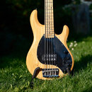 Fotografie znázorňuje tělo čtyřstrunné basové kytary z přírodního světlého dřeva s viditnou masivním kresbou. Nástroj má černý plastový pickguard, dv…