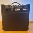 Zadní strana černého basového komba s rukojetí. Na horním štítku je uveden model CM20B, popis 20W BASS AMPLIFIER a výrobce CORT MUSICAL INSTRUMENTS M…