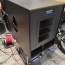 Černý aktivní subwoofer v hranatém korpusu s matným povrchem. Na horním pravém rohu je modro-bílé logo s nápisem MACKIE Active. Přední strana obsahuj…