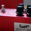Červený kytarový efekt v kovovém krytu. Na boku je bílá nálepka s nápisy Supro, Model: 1313 Delay, S/N: 0358 a symboly RoHS CE. Horní panel obsahuje…