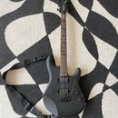 Černá elektrická kytara s matným povrchem a tmavým hnedým hmatníkem. Na hlavě je bílý nápis Ibanez a na těle jsou dva humbuckery, ovládací knoflíky a…