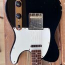 Černá elektrická kytara typu Telecaster s bílým pickguardem a hnedým hmatníkem. Na kovovém panelu jsou dva černé oválné knofíky a přepínač. Lak na ho…
