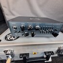 Šedý kytarový pedál značky DARKGLASS ELECTRONICS, model ALPHA·OMEGA. Na horní části jsou nápisy INPUT, COMP, DRIVE a LEVEL u ovládacích knoflíků, dál…