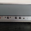 Zadní panel kytarového komba v šedé barvě. Jsou zde viditelné nápisy „6 Ω“, „1.5 Ω“, „REVERB“, „VIBRATO“, „PRESENCE“ a v pravém dolním rohu text „MAD…
