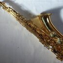 Zlatý saxofon s kovovým povrchem. Nástroj je v celkově čistém stavu bez viditelných poškzení nebo výrazného opotřebení. Na těle nástroje nejsou vidět…