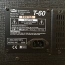 Detailní záběr na zadní štít černého kytarového komba. Na štítku je uvedeno logo VOX, nápis Vox Amplification Ltd. Manufactured in Korea, Model No. T…
