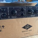 Černý rackový audio přístroj s dvěma moduly, umístěný na kartonové krabici. Levý modul nese nápis UNIVERSAL AUDIO 610 Tube Preamplifier a pravý UNIVE…