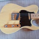 Světlé elektrické kytary typu Telecaster s černým pickguardem. Nástroj má dřevěný krk a hmatník v přírodní barvě. Na těle nejsou vidět žádná loga ani…