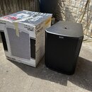Na fotografii je černý aktivní subwoofer a jeho originální kartónová krabice. Na reproduktoru je v horní části logotyp ALTO. Krabice obsahuje nápisy…