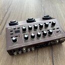 Hnědý kytarový předzesilovač s nápisem Acoustic Preamp AD-10 a logem BOSS. Zařízení obsahuje řadu ovládacích knoflíků, přepínačů a vstupních/výstupní…