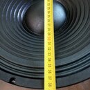 Detailní pohled na černý reproduktor s žlutýmv metrů, který je přiložen k měření průměru. Na membráně a okraji nejsou vidět žádné značky ani nápisy.…