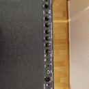 Detailní pohled na ovládací panel černého zesilovače s texturou. Na panelu jsou nápisy INPUT, ACTIVE EQUALIZER a OUTPUT spolu s řadou ovládacích knof…