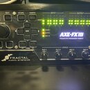 Čelní panel černého rackového procesoru s nápisy AXE-FX III a PREAMP/FX PROCESSOR-MARK II. V levé dolní části je logo a text FRACTAL AUDIO SYSTEMS. Z…