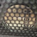 Fotografie zachycuje detail štítku reproduktoru viditelný skrz kovovou mřížku. Na štítku je uvedeno "Model 12 M Greenback", "Power capacity 25 watt"…