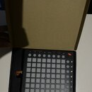 Černý MIDI kontrolér Novation Launchpad Mini v originální kartónové krabici. Zařízení obsahuje mřížku 8x8 bílých podsvícených políček a několik ovlád…