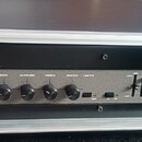 Černý basový zesilovač Ampeg B2R umístěný v hliníkovém transportním kufru. Na předním panelu jsou ovládací prvky s nápisy INPUT, PAD, GAIN, BASS, ULT…