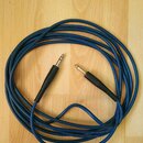 Modrý instrumentální kabel s konektory typu jack. Konektory mají zlatavý povrch a černé plastové úchyty. Na modrém oplotu je bílý nápis "Hotone Noise…