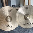 Dvě mosazné činely s viditelným ručním broušením. Oba nesou nápis istanbol Handmade cymbals from Turkey. Levý činel má nápisy 35 cm 14", HI-HAT BOTTO…