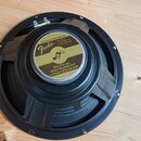 Černý reproduktor s kovovým rámem a montážními otvory v obvodu. Na středovém zlatavě-zeleném štítku je logo Fender a nápisy SPECIALLY DESIGNED FOR MU…