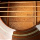 Detailní pohled do otvoru akustické kytary s viditelným vnitřním dřevěným dnem a žebrováním. Na vnitřní desce je razítko s nápisy SIGMA GUITARS, MADE…