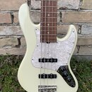 Bílá elektrická basová kytara s hnědým hmatníkem z tmavého dřeva. Nástroj má perleťový pickguard a dva černý snímače. Na těle jsou tři černé oválné o…