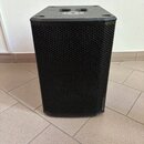 Černý reproduktor v hranatém korpusu s texturovaným povrchem a přední kovovou mřížkou s voštinovým vzorem. Horní plocha obsahuje vlisované kovové prv…