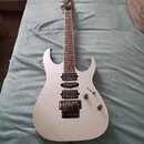 Bílá elektrická kytara s dvojcutem a hnedým hnedým hmatníkem. Na všech třech snímačích je nápis DiMarzio. Kytara má Floyd Rose systém, jeden přepínač…