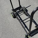 Černý transportní vozík z kovových profilů s dvěma pneumatickými koly s limeňkovým žlutým ráfkem. Konstrukce tvoří základna s příčkami a vyklápěcí ru…