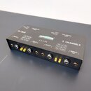 Černá DI-box s nápisy DI-BOX, BALANCED OUT a 2 CHANNELS. Na horní straně je logo COROTAL SOUND & AUDIO EQUIPMENT a označení modelu CES 02. Zařízení o…