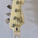 Fotografie zachycuje hlavu basové kytary v krémové barvě s chromovanými ladičkami. Na povrchu je černý nápis Fender® PRECISION BASS. Krk nástroje je…