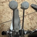 Fotografie zachycuje detail mechanismu bicího pedálu z kovu v stříbrné barvě. Na bočním krytu je svisle napsán nápis Iron Cobra. Pedál vykazuje známk…