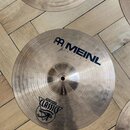 Fotografie zobrazuje dva kovové činely v tradičním zlatavě hnědém odstínu s viditelným rýhováním. Na spodním činele je nápis MEINL a logo značky, dál…