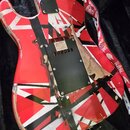 Zadní strana elektrické kytary s červeno-bílo-černým vzorem připomínajícím Union Jack. Tělo vykazuje výrazné opotřebení, s odloupanou barvou a vidite…