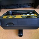 Černý elektronický modul s žlutým ovládacím panelem. Na panelu jsou nápisy TRIGGER MODULE TM-2, KIT, MUTE a tlačítka SETUP, SOUND, INST. Zařízení je…