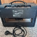 Černý kytarový kombozesilovač s koženkovým potahem a přenosnou rukojetí. Na zadním panelu je štítek s nápisy: Roland, PathFinder 10, Model No. V9110,…
