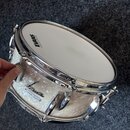 Bílý buben s perleťovým povrchem a chromovaným kováním. Na blaně je nápis EVANS G2, na korpusu jsou nápisy SONOR Vintage Superprofi a logo Sonor. Pov…