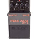Šedý efekt pedál s nápisy Metal Zone a MT-2. Na horní části jsou čtyři ovládací knoflíky s popisky LEVEL, EQUALIZER (HIGH, LOW, MIDDLE, MID FREQ) a D…
