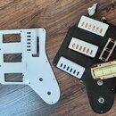 Dvě plastové krycí desky (pickguardy) na elektrickou kytaru, jedna bílá a jedna černá. Černý pickguard obsahuje tři bílé plastové kryty snímačů a jed…